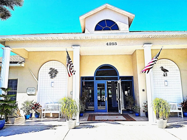 entrance to property featuring a porch and stucco siding
