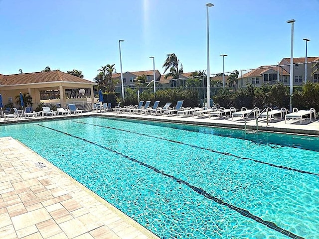 community pool featuring fence, a patio, and a residential view