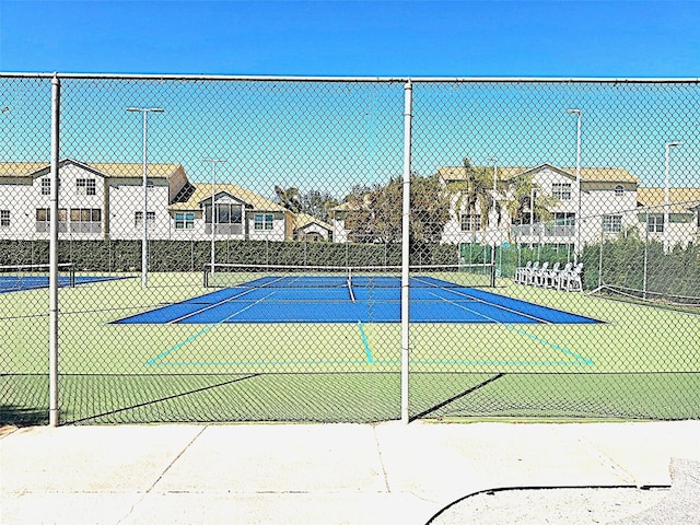 view of sport court with fence and a residential view