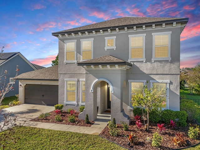 view of front facade with an attached garage, driveway, and stucco siding