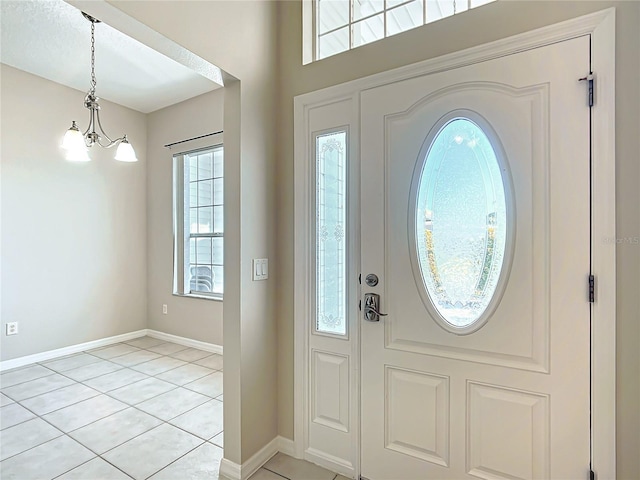 foyer entrance featuring a chandelier, baseboards, and light tile patterned flooring