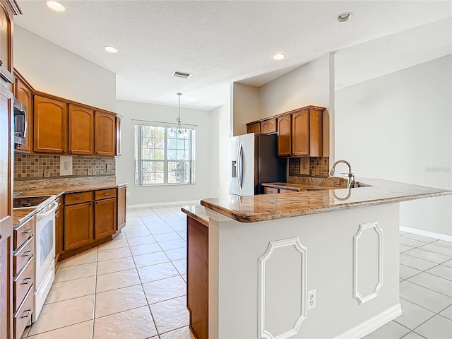 kitchen with visible vents, light tile patterned floors, brown cabinets, a peninsula, and stainless steel appliances