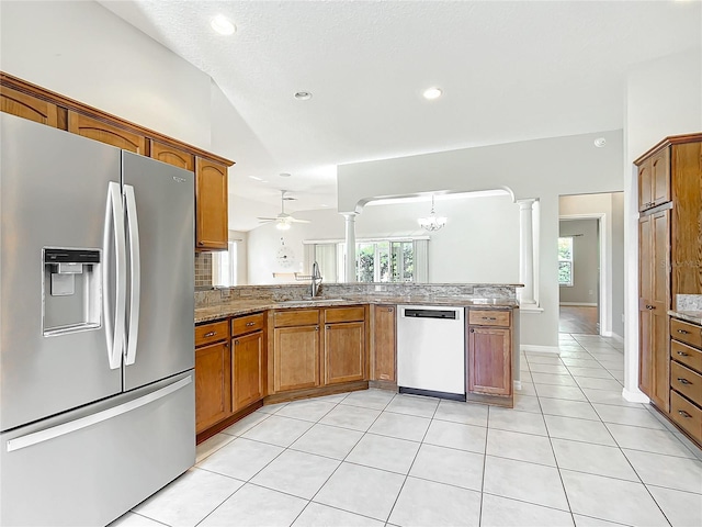 kitchen with brown cabinets, appliances with stainless steel finishes, ornate columns, and a sink