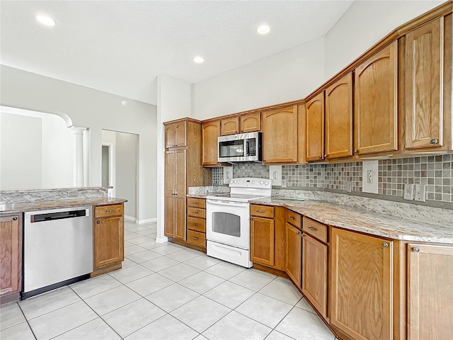 kitchen featuring light stone counters, stainless steel appliances, tasteful backsplash, and light tile patterned floors