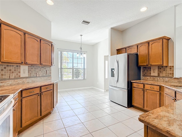 kitchen with white electric range, visible vents, brown cabinetry, and stainless steel fridge with ice dispenser