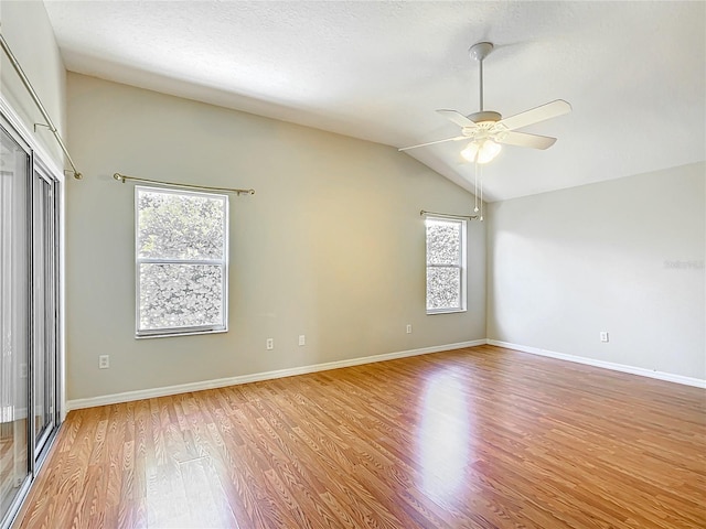 empty room featuring vaulted ceiling, light wood-style flooring, baseboards, and ceiling fan