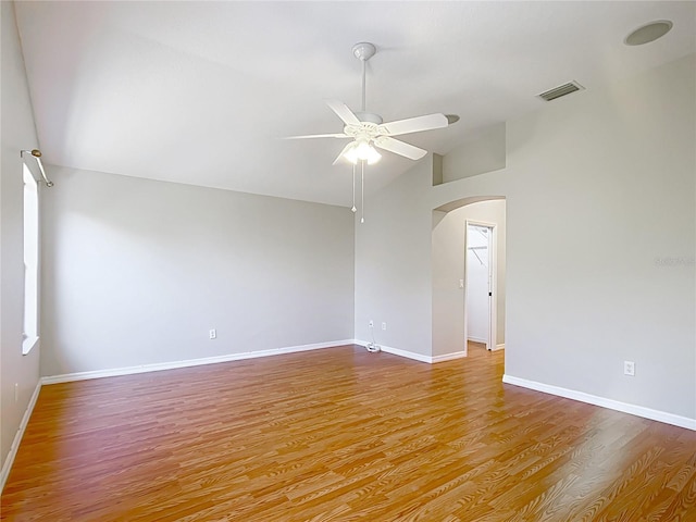 spare room with visible vents, ceiling fan, lofted ceiling, wood finished floors, and arched walkways