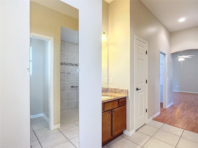 full bathroom featuring tile patterned flooring, baseboards, a tile shower, vanity, and a ceiling fan