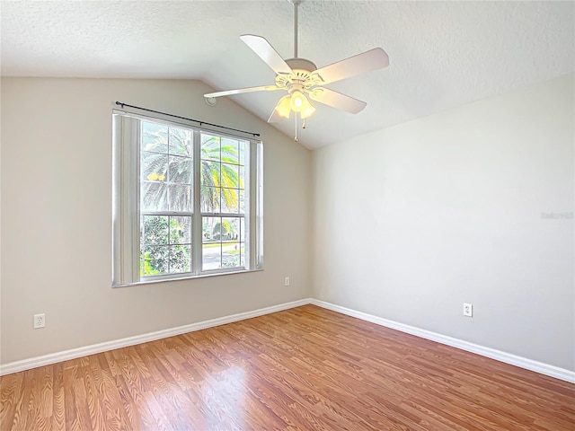 spare room featuring lofted ceiling, a textured ceiling, wood finished floors, baseboards, and ceiling fan