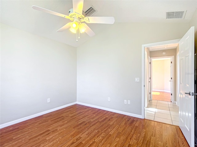 unfurnished room with light wood-type flooring, visible vents, a ceiling fan, baseboards, and lofted ceiling