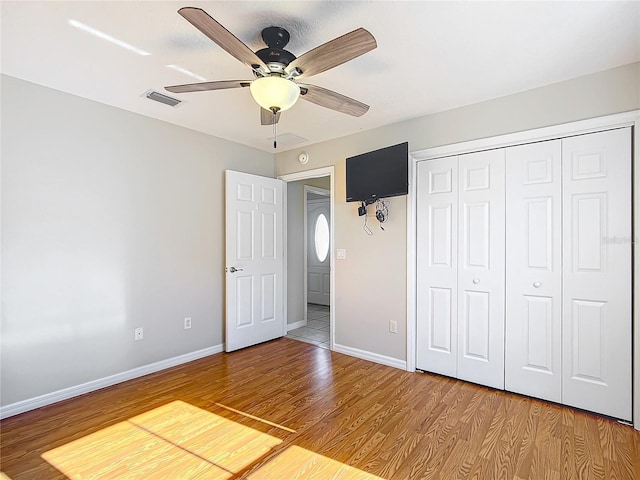 unfurnished bedroom with light wood-type flooring, visible vents, a ceiling fan, a closet, and baseboards