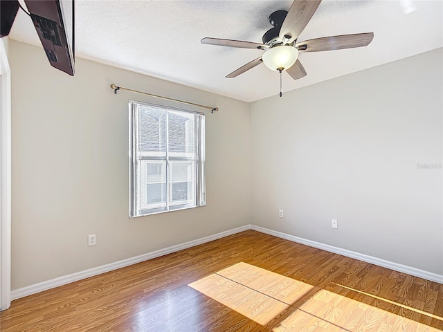 unfurnished room with baseboards, wood finished floors, and a ceiling fan