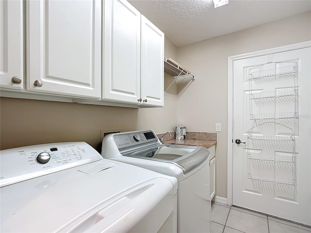 laundry room with washer and dryer, light tile patterned flooring, cabinet space, and a textured ceiling