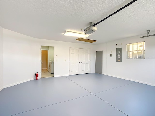 garage featuring electric panel, washer / clothes dryer, a garage door opener, and baseboards