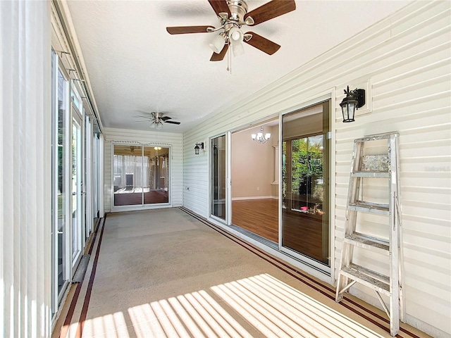 unfurnished sunroom with ceiling fan with notable chandelier