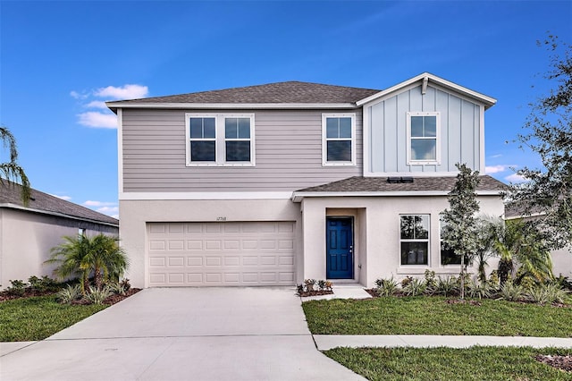 traditional home with an attached garage, a shingled roof, concrete driveway, a front lawn, and board and batten siding