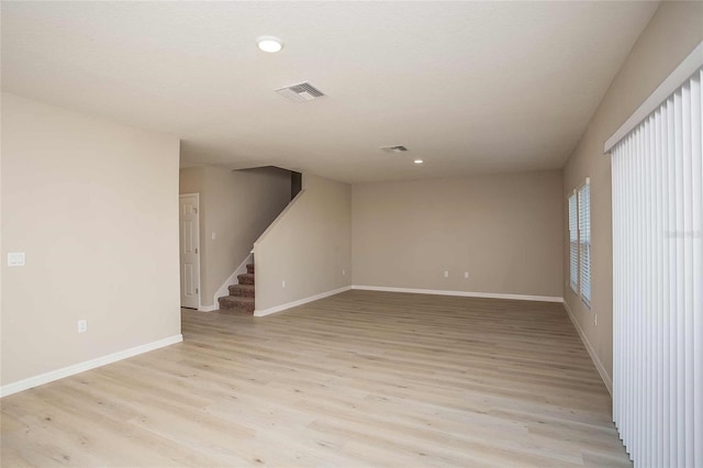 empty room featuring light wood-style flooring, recessed lighting, visible vents, baseboards, and stairway