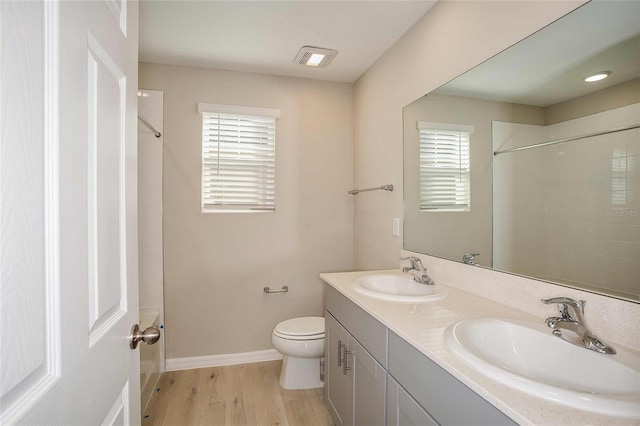 bathroom with a shower, wood finished floors, a sink, and toilet