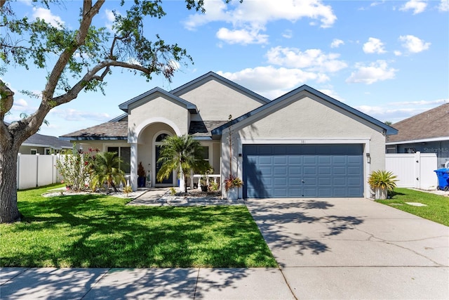 ranch-style home featuring fence, driveway, stucco siding, a front lawn, and a garage