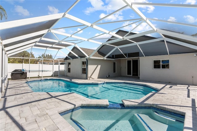 view of swimming pool with a patio, fence, a lanai, and a pool with connected hot tub