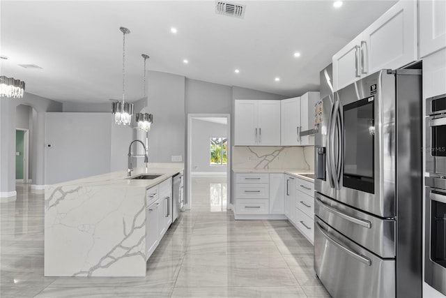 kitchen with light stone counters, visible vents, arched walkways, a sink, and appliances with stainless steel finishes