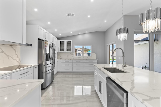 kitchen with light stone countertops, visible vents, a sink, white cabinets, and appliances with stainless steel finishes