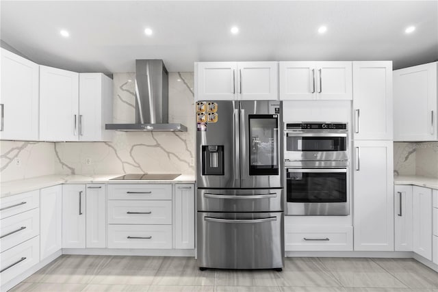 kitchen with light stone counters, white cabinets, wall chimney exhaust hood, and stainless steel appliances