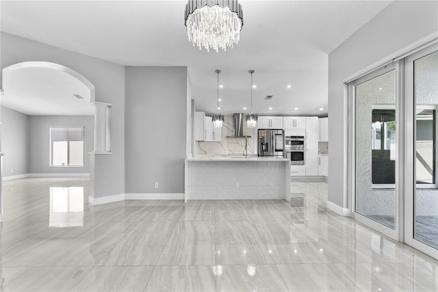 unfurnished living room featuring recessed lighting, baseboards, arched walkways, and an inviting chandelier