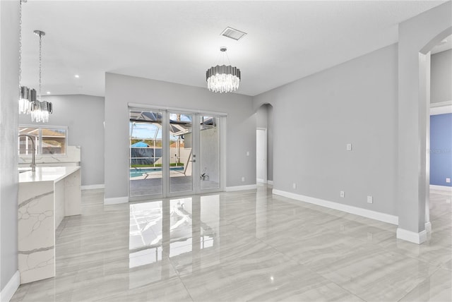 unfurnished dining area with arched walkways, visible vents, baseboards, and an inviting chandelier