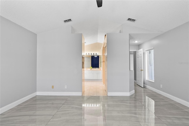 spare room with visible vents, baseboards, a textured ceiling, and lofted ceiling