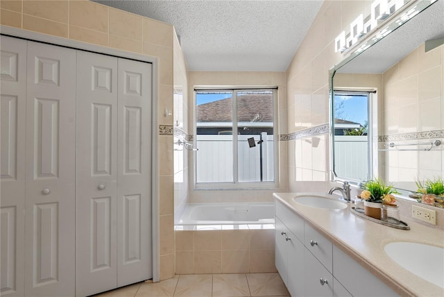 full bathroom with a closet, a textured ceiling, a bath, and a sink