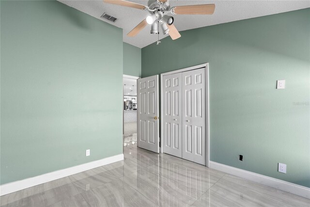 unfurnished bedroom with baseboards, visible vents, lofted ceiling, a closet, and a textured ceiling