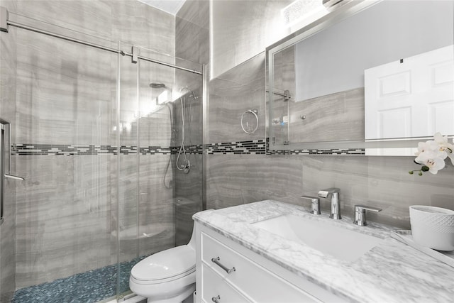 full bath with toilet, tile walls, a stall shower, and vanity