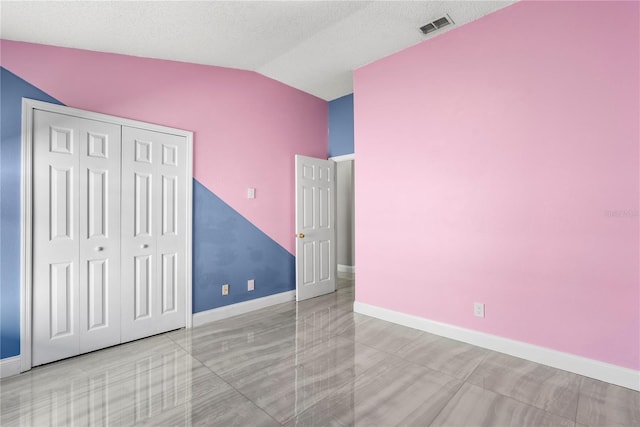 unfurnished bedroom featuring baseboards, visible vents, lofted ceiling, and a closet