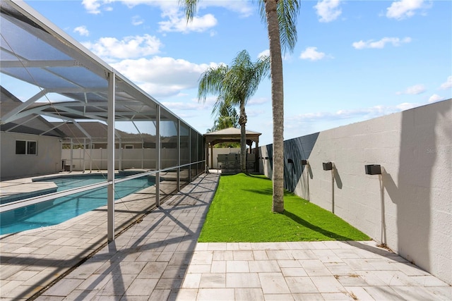 view of swimming pool with glass enclosure, a patio, a yard, and a fenced backyard