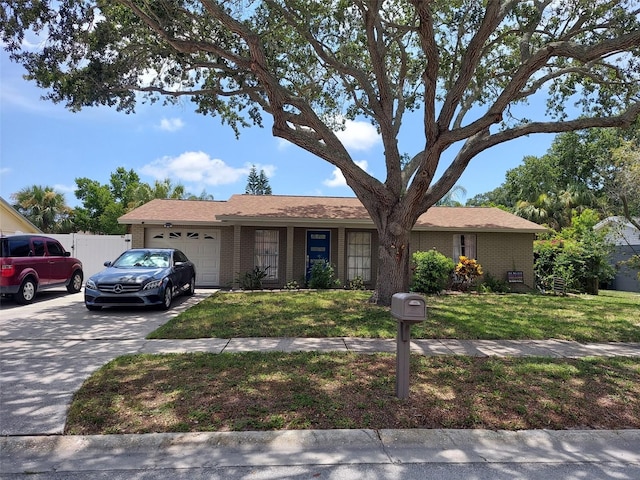 ranch-style house featuring a garage, concrete driveway, brick siding, and a front lawn