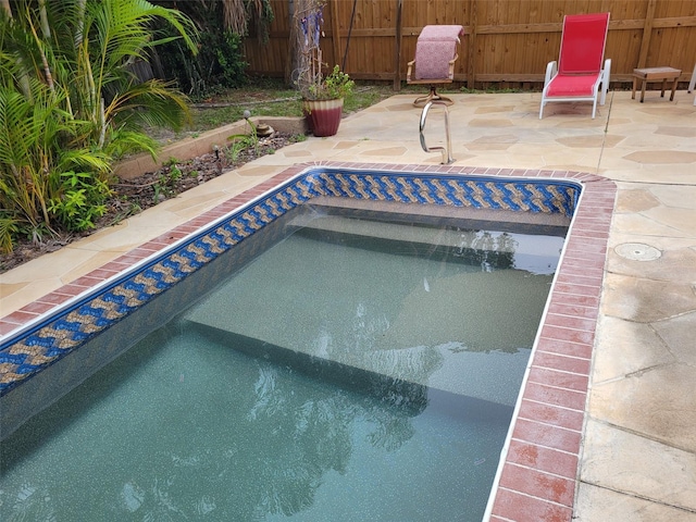 view of swimming pool with a hot tub, fence, and a patio