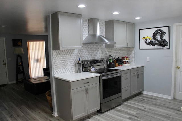 kitchen with stainless steel electric range oven, wall chimney range hood, and gray cabinetry