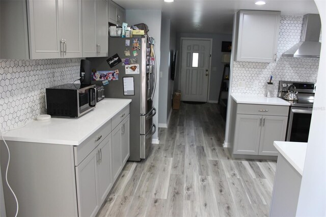 kitchen with wall chimney exhaust hood, appliances with stainless steel finishes, and gray cabinetry