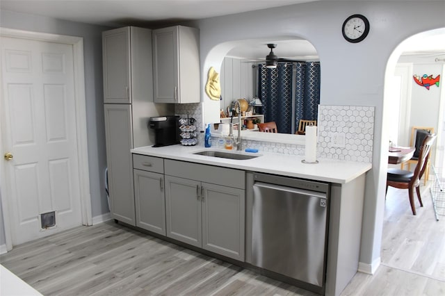 kitchen featuring light wood finished floors, gray cabinets, light countertops, stainless steel dishwasher, and a sink