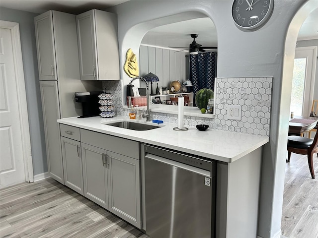 kitchen featuring a ceiling fan, dishwasher, light countertops, gray cabinetry, and a sink