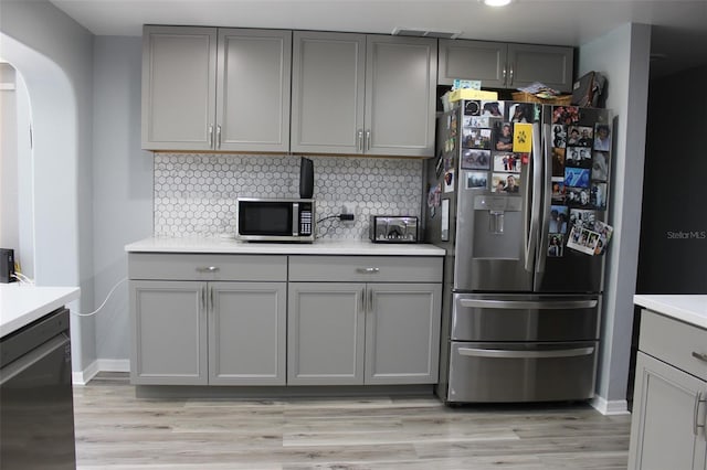 kitchen with gray cabinets, arched walkways, and stainless steel appliances