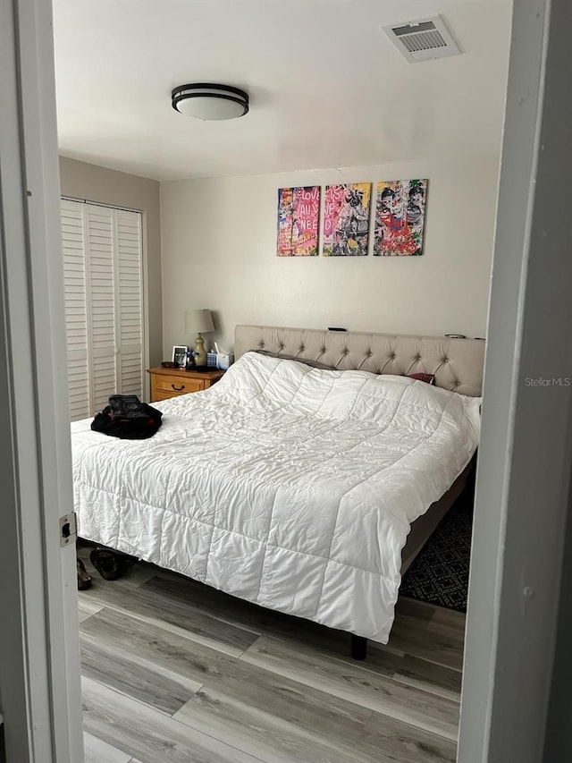 bedroom featuring a closet, visible vents, and wood finished floors