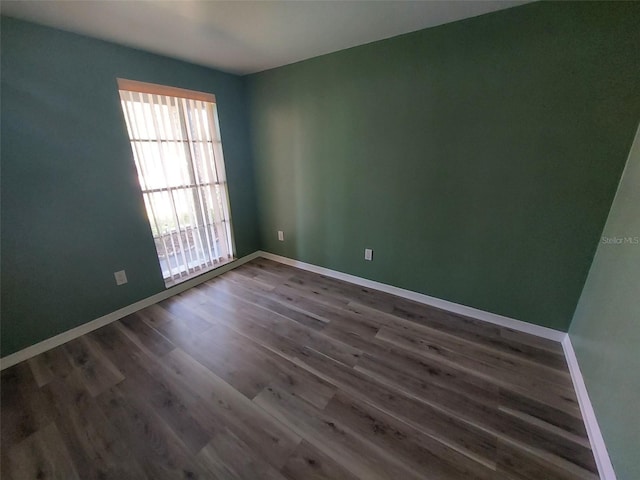 empty room featuring dark wood-style flooring and baseboards