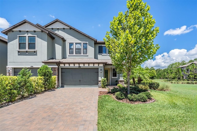 view of front of property with a front yard, decorative driveway, an attached garage, and stucco siding