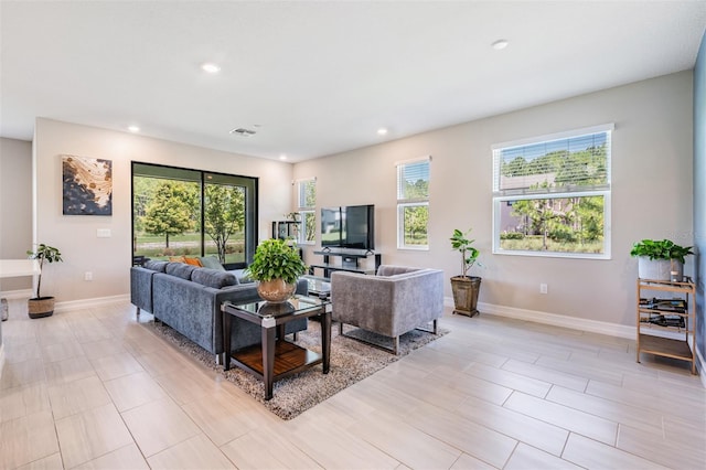 living area with a wealth of natural light, visible vents, baseboards, and recessed lighting