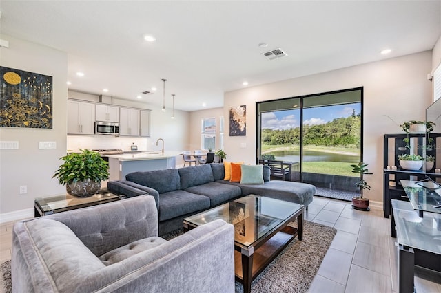 living room featuring light tile patterned floors, baseboards, visible vents, and recessed lighting