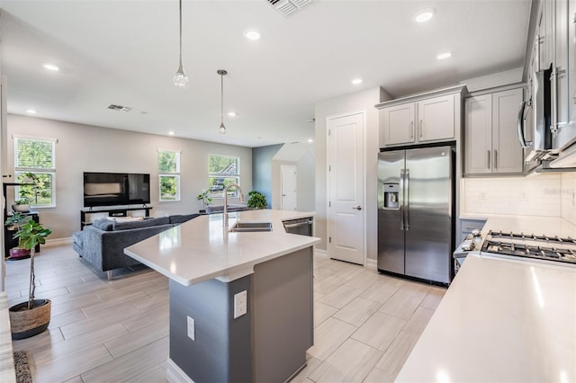 kitchen featuring gray cabinetry, stainless steel appliances, a sink, light countertops, and tasteful backsplash