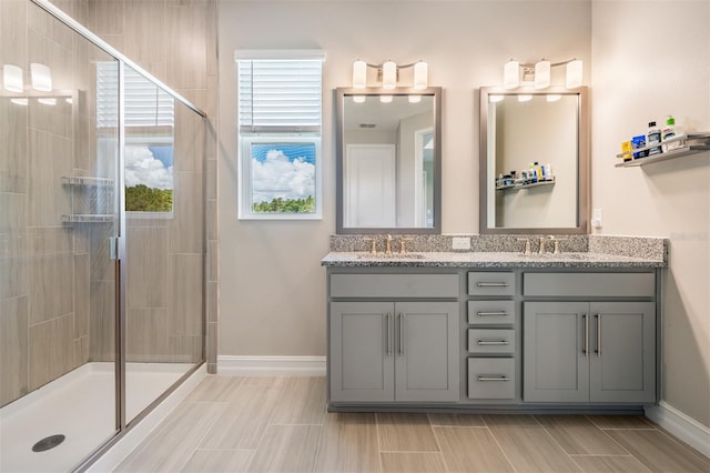 bathroom featuring double vanity, a stall shower, and a sink