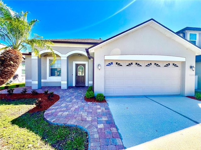 ranch-style home featuring driveway, an attached garage, and stucco siding